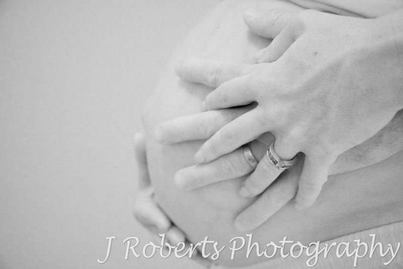 B&W of pregnant belly with parents hands on it - pregnancy photography sydney